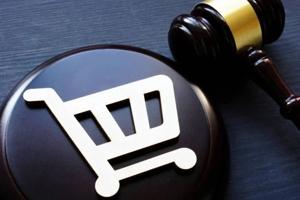 A shopping trolley symbol on a sound block beside a gavel, representing consumer and commercial law